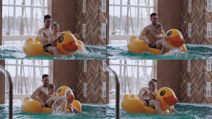 游泳池里的家庭娱乐，父亲和小儿子漂浮在有趣的橡皮鸭上，笑着
