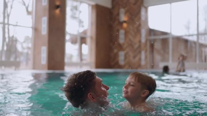 假期的周末，小男孩和他的父亲在现代酒店的游泳池里游泳和玩耍