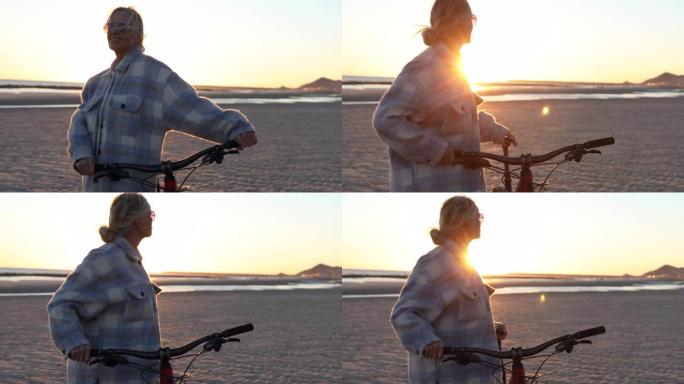 女骑自行车的人从海滩观看日出，然后出发
