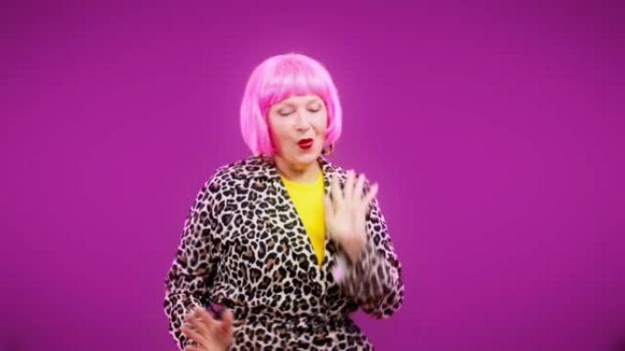 假发中的古怪成熟女人跳舞和微笑，庆祝成功或假期