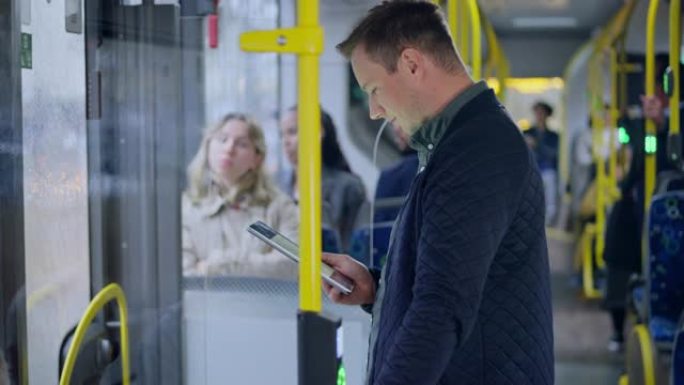 LD男子站在公共汽车上并使用他的数字平板电脑