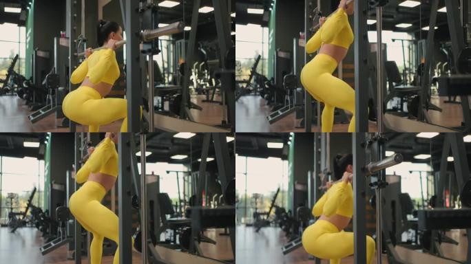 在健身房或健身俱乐部使用机上健身史密斯机锻炼西班牙裔年轻女性锻炼身体肌肉。女孩用杠铃在肩膀上举重，同