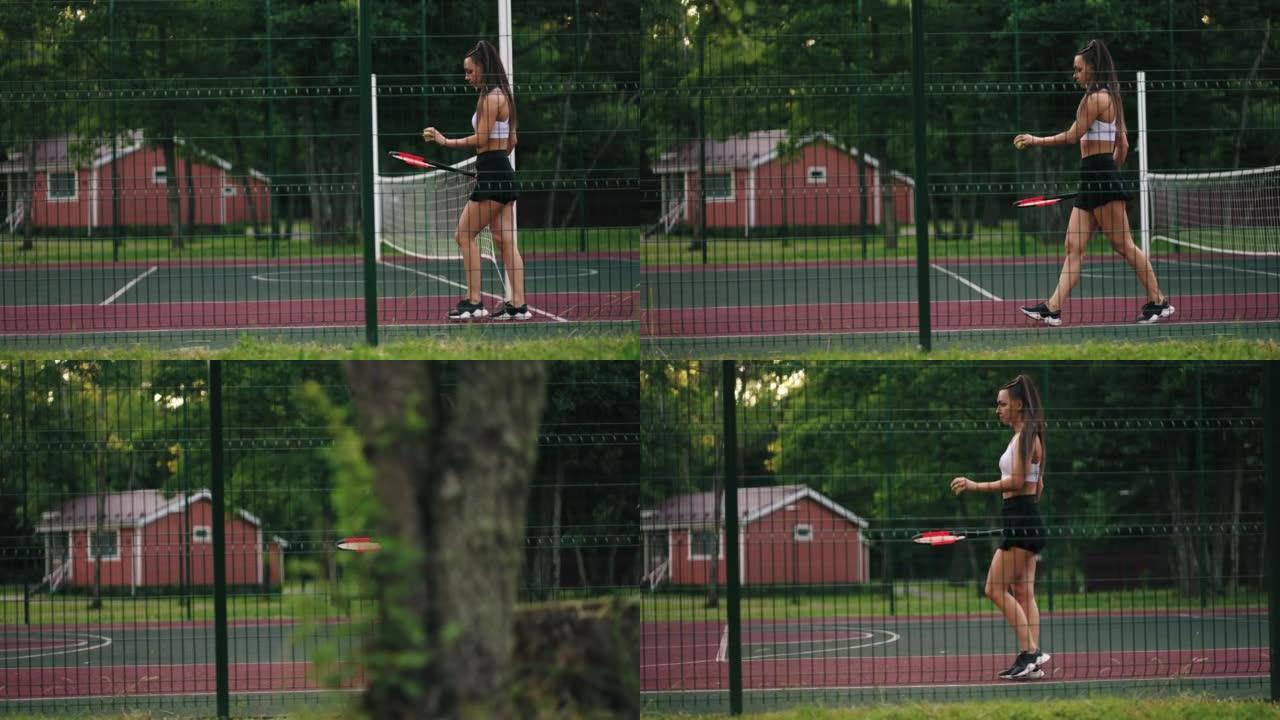 马尾辫性感的运动型女士独自在网球场上训练，用球拍走路和击球