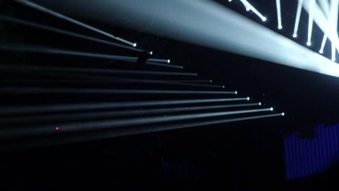 风景秀丽的聚光灯在黑暗的舞台上发出蓝光。现代照明设备。闪亮的线条飞过黑暗的背景。舞台灯光设备。