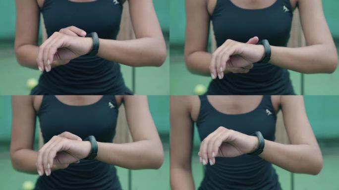 亚洲女子在开始网球比赛前设置他的智能手表来衡量她的健康状况。