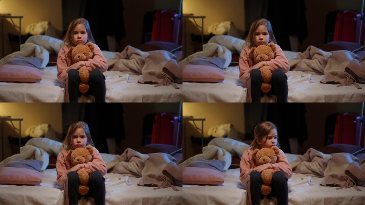 紧张害怕的乌克兰女孩拥抱泰迪熊看着坐在防空洞里的相机的肖像。惊吓迷人的孩子在空袭警报警告中躲藏起来躲
