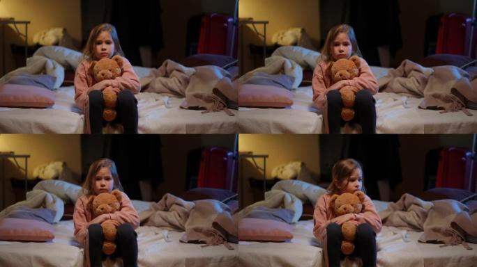 紧张害怕的乌克兰女孩拥抱泰迪熊看着坐在防空洞里的相机的肖像。惊吓迷人的孩子在空袭警报警告中躲藏起来躲