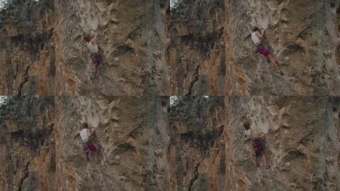 空中无人机拍摄了一名女子攀爬在红色岩壁上的岩石
