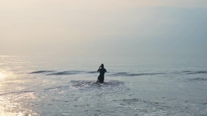 游泳训练。波浪中的女人剪影