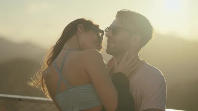 热爱游客的浪漫情侣在日落时拥抱和亲吻