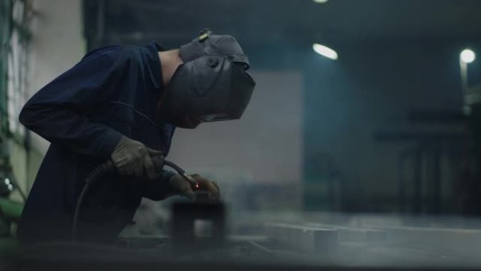 肖像一名工人在工厂工作，以慢动作焊接钢金属零件。火花飞舞