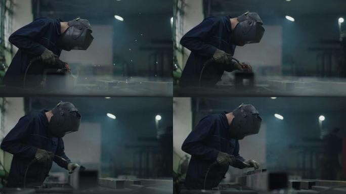 肖像一名工人在工厂工作，以慢动作焊接钢金属零件。火花飞舞