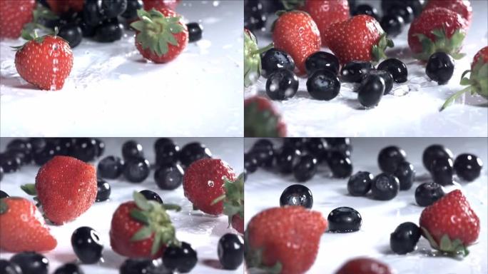 蓝莓和草莓在白色背景上滚动。慢动作