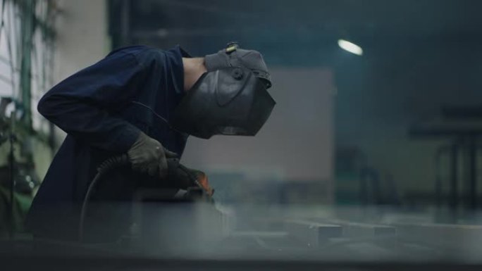 一名男性焊工在工厂工作，以慢动作焊接钢金属零件。火花飞舞