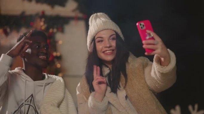 不同种族和种族的学生在露天圣诞晚会上通过智能手机自拍