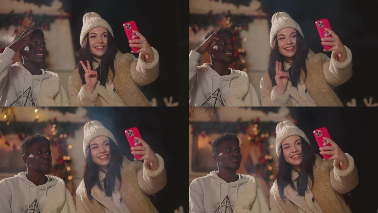 不同种族和种族的学生在露天圣诞晚会上通过智能手机自拍
