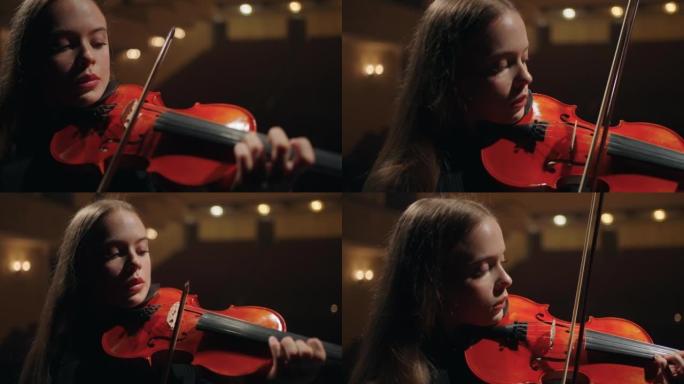 年轻的女小提琴演奏家在音乐厅演奏奏鸣曲，女小提琴家的特写肖像