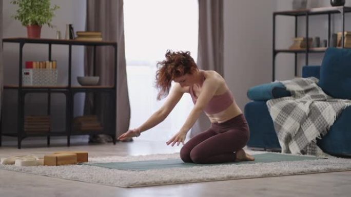 女人早上在公寓的客厅里做哈塔瑜伽练习，在公寓里拍摄全长照片
