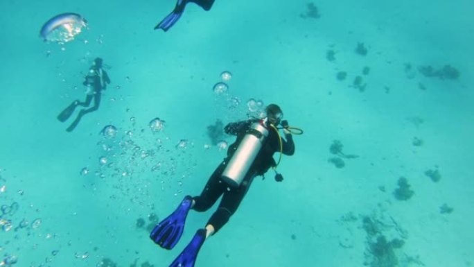 探索红海的潜水点。潜水员向海底下降，气泡接触相机镜头