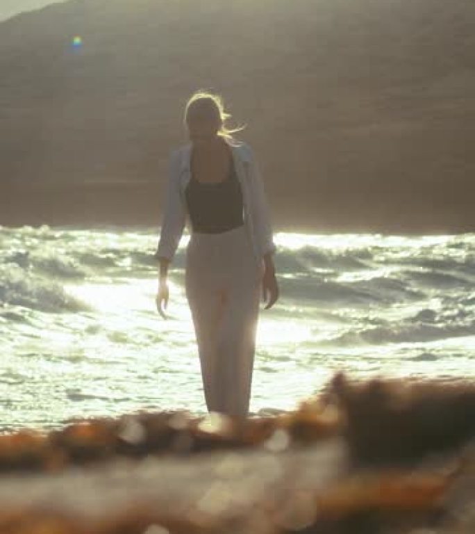 女人独自走在海滨悬崖上。望向遥远的大海欣赏风垂直视频