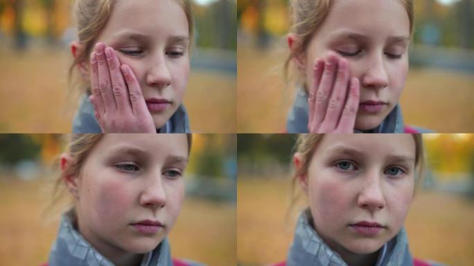 悲伤沮丧可爱的青少年女学生触摸脸颊，表情沮丧地看着相机。被欺负的高加索少女在校园里摆姿势的特写肖像。