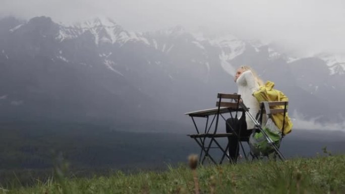 女人在便携式桌子上放松，俯瞰森林，山脉