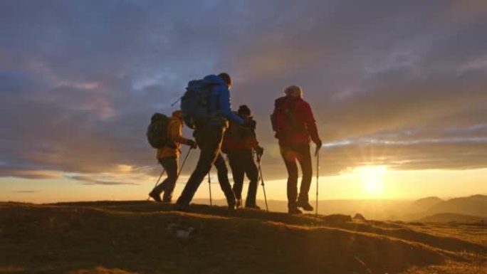 空中SLO MO四名徒步旅行者在日落时走在山顶上