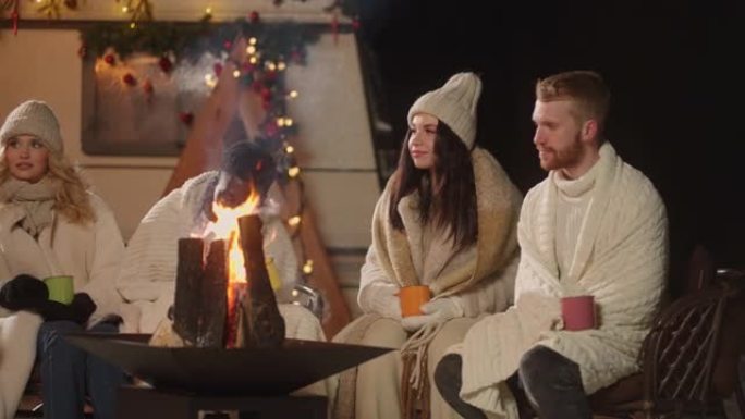 大自然乡村的圣诞晚会，年轻漂亮的人坐在户外壁炉旁