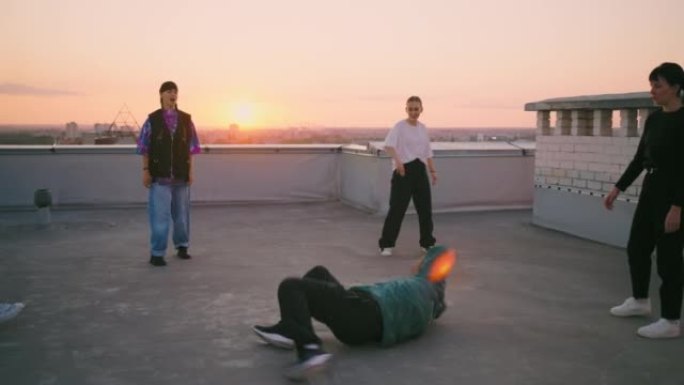 酷的霹雳舞男孩在屋顶上跳舞，穿着时髦连帽衫的年轻人在地板上跳舞，朋友舞会