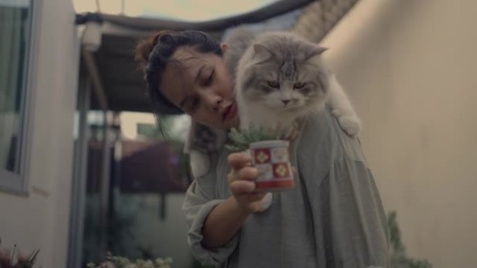 女人在花园里向猫展示植物