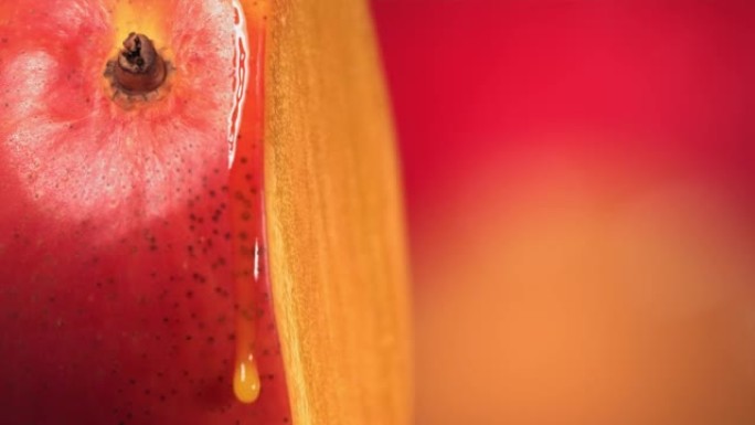 一滴芒果汁从旋转减半的芒果王表面流下。慢动作