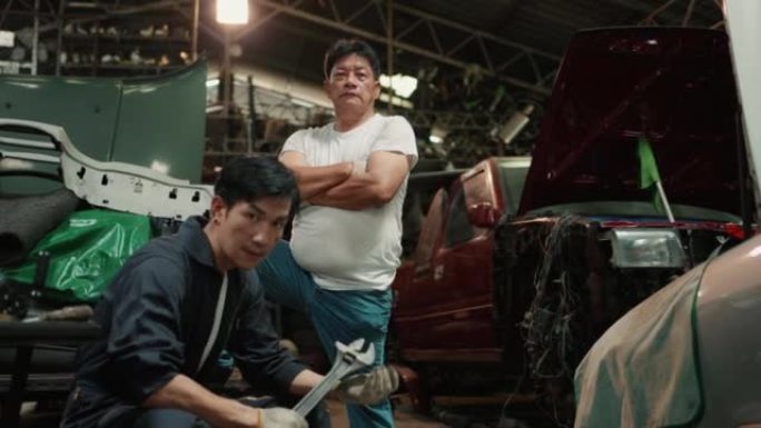高级机械师和他的儿子在汽车服务中对着相机摆姿势的肖像
