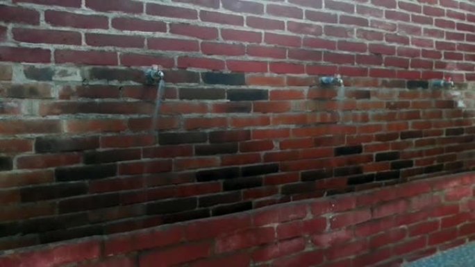 水从附在砖墙上的水龙头流出