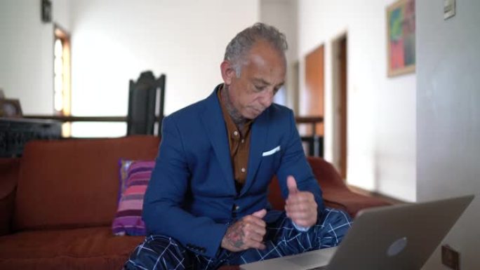 商人在家工作，在参加视频通话时使用pajamas的裤子