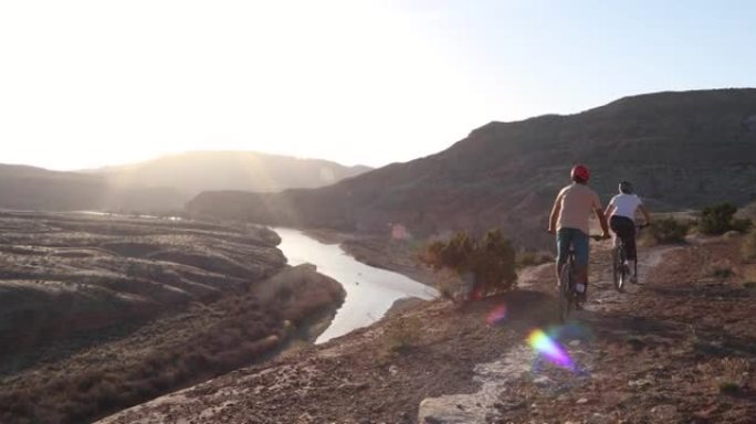 成熟的山地自行车夫妇沿着沙漠小路，经过岩石
