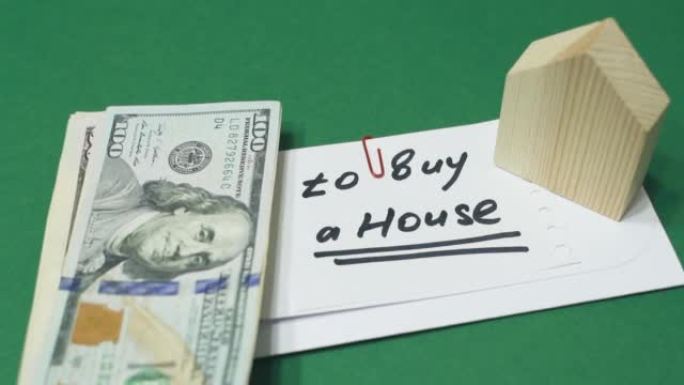 一个人把美元放在一个有铭文的信封附近-买房。
