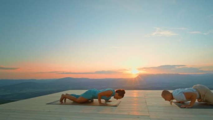 CS男女在日落时在山上做瑜伽动作