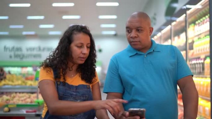 在超市购物时使用智能手机的家庭