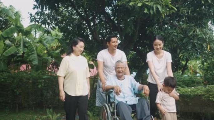 欢快的家庭推着年迈的父亲坐在家里的轮椅上。