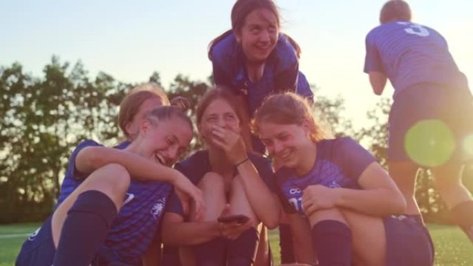 女子足球队在智能手机上观看视频并大笑
