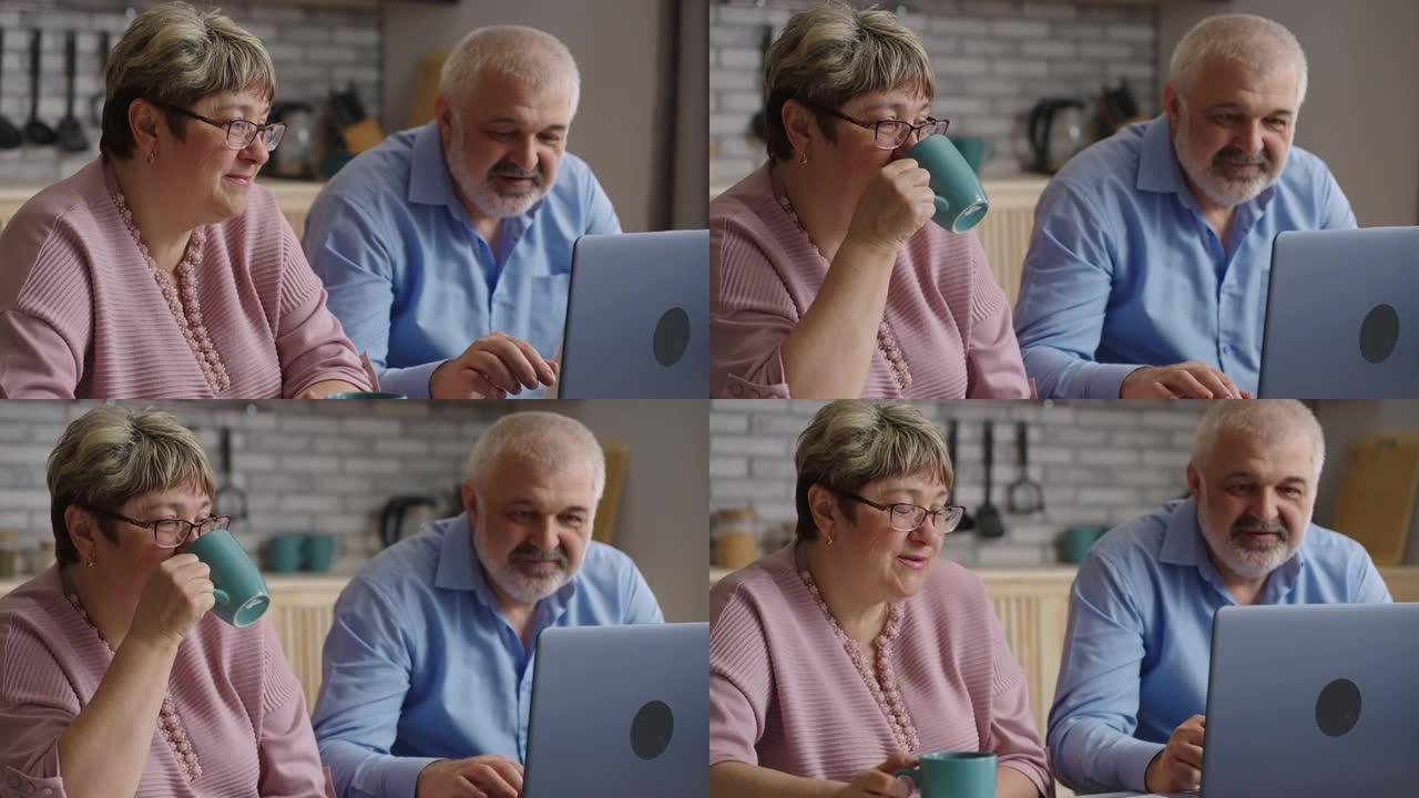退休人员正在学习使用笔记本电脑，通过现代笔记本电脑在家庭厨房上网，微笑的老年配偶正在看屏幕