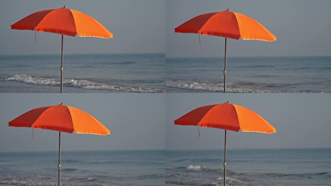 一把橙色的沙滩伞对着海浪，以慢动作射击。
