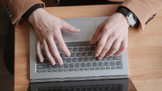 成功的商人正在使用笔记本电脑，在键盘上键入消息，双手特写