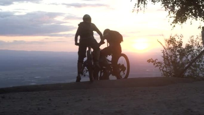 三个朋友在日落时开始下坡山地自行车冒险