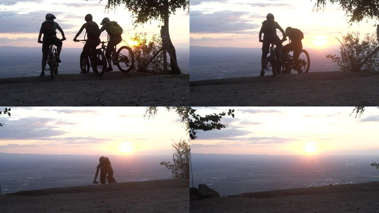 三个朋友在日落时开始下坡山地自行车冒险