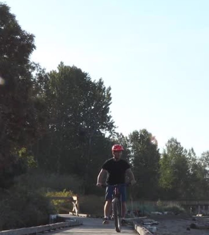 男性骑自行车的人在森林环境中跟随木板路