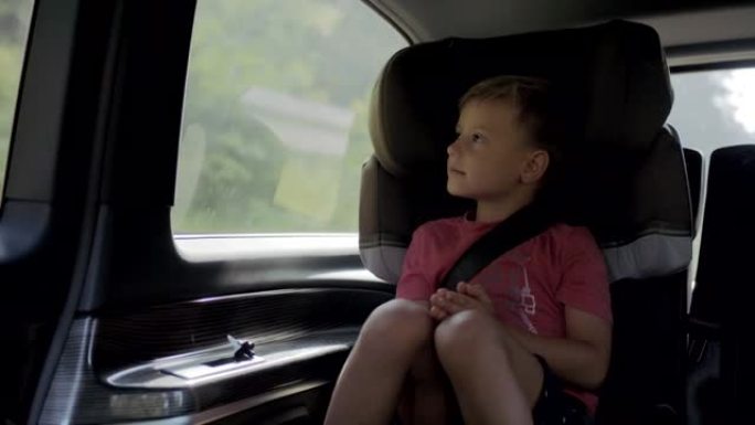 一个小男孩坐在车里看着窗外的细节照片
