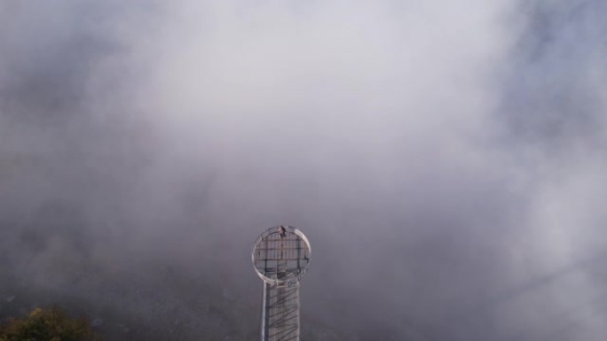 空中无人机拍摄的一名男子站在山腰云层上方的人行道上