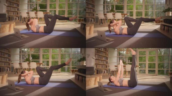 女运动员在瑜伽垫上做腹肌。家庭锻炼