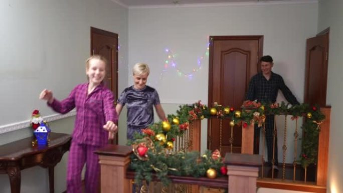 兴奋的少女女人和男人在圣诞节早上醒来，在室内的家楼下散步。快乐开朗的高加索女儿父亲和母亲欢欣鼓舞新年